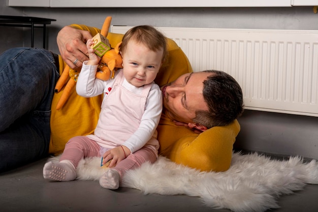 Jeune papa avec sa fille mignonne et heureuse sur fond noir. Père et petite fille d'un an.