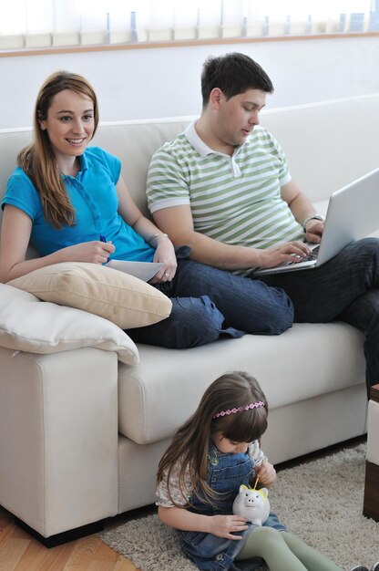 Photo jeune parent à la maison avec un bel enfant faire des économies et mettre de l'argent dans une tirelire