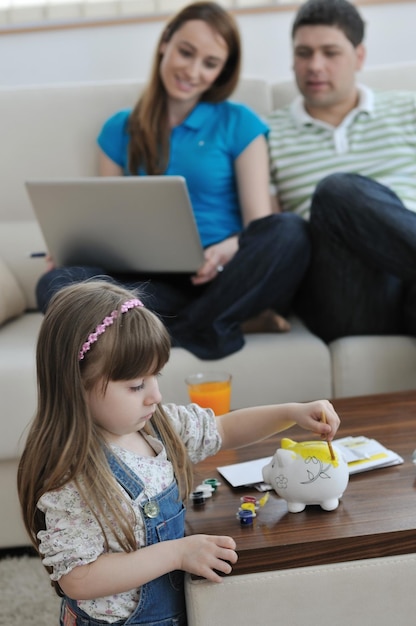 Photo jeune parent à la maison avec un bel enfant faire des économies et mettre de l'argent dans une tirelire