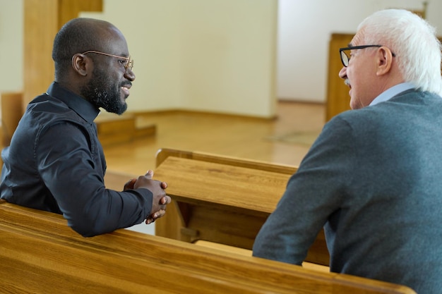 Jeune pasteur afro-américain consultant un paroissien senior à l'église