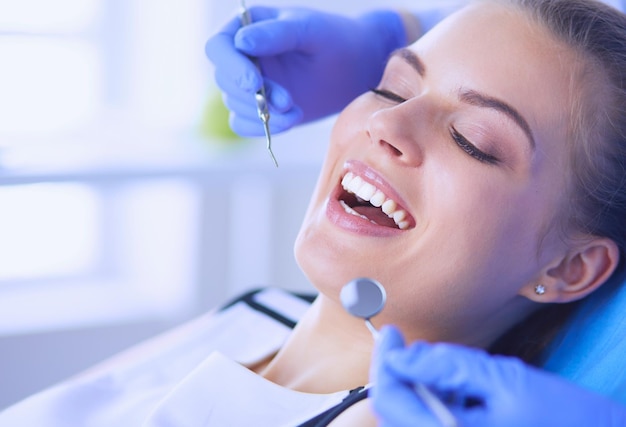 Jeune patiente avec la bouche ouverte examinant l'inspection dentaire au bureau du dentiste