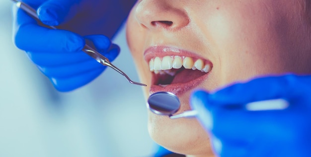 Jeune patiente avec la bouche ouverte examinant l'inspection dentaire au bureau du dentiste