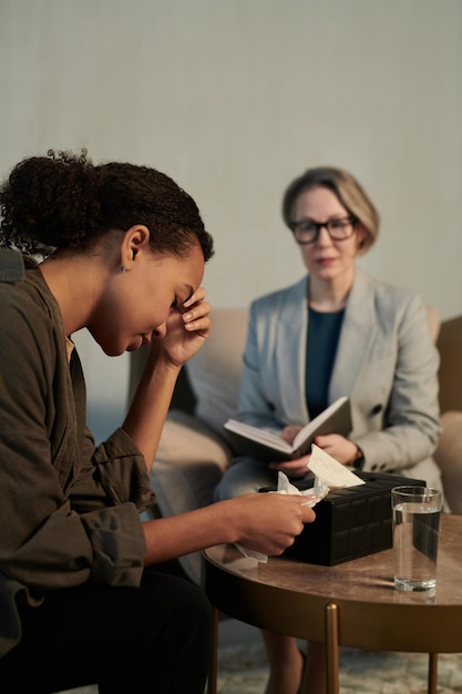 Jeune patiente déprimée touchant la tête pendant la séance psychologique