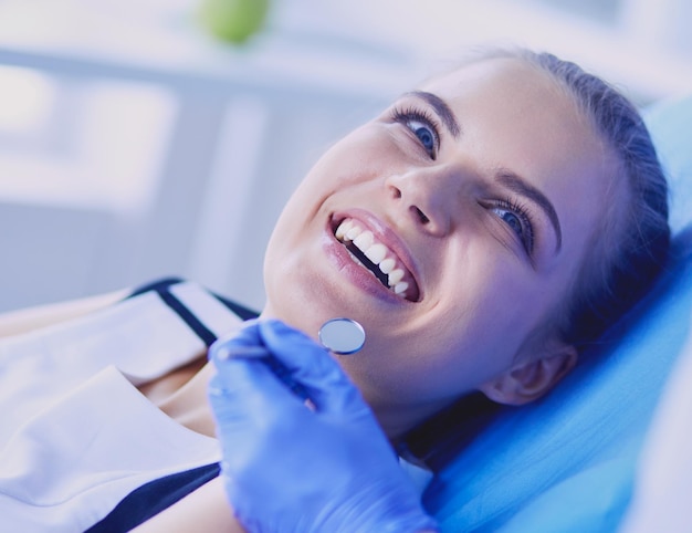 Jeune patiente avec un joli sourire examinant l'inspection dentaire au bureau du dentiste