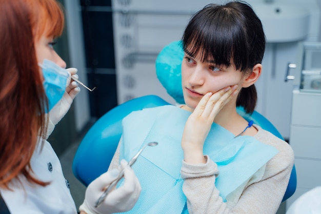 Jeune patiente montre le dentiste à ses douleurs dentaires en stomatologie.