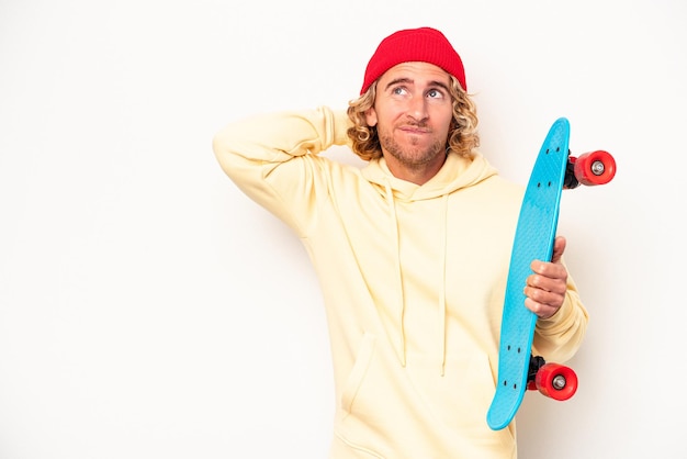 Jeune patineur caucasien isolé sur fond blanc touchant l'arrière de la tête, pensant et faisant un choix.