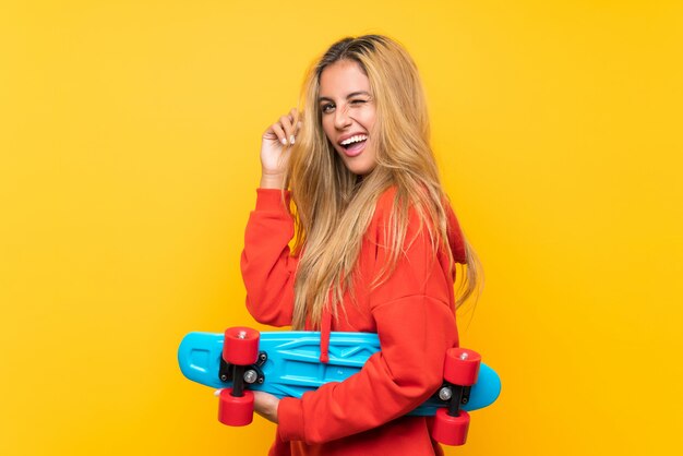 Jeune patineur femme sur fond jaune isolé