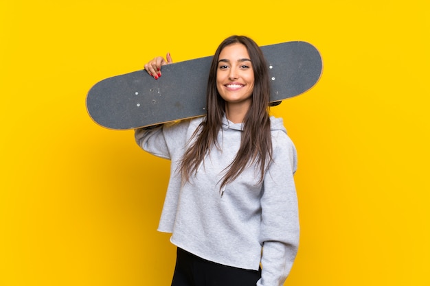 Jeune patineur femme sur mur jaune isolé