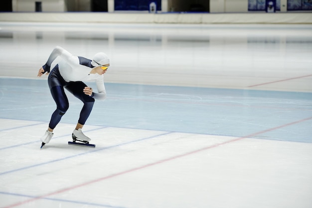 Jeune patineur de vitesse se penchant vers l'avant tout en faisant de l'exercice sur une patinoire