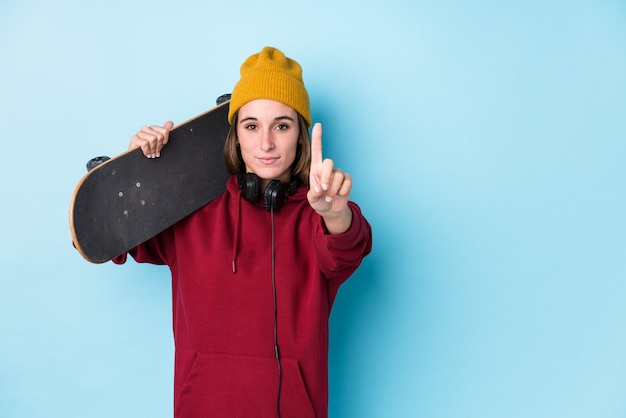 Jeune patineuse caucasienne femme montrant le numéro un avec le doigt.