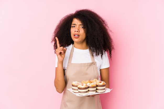 Jeune pâtissier afro femme tenant des cupcakes