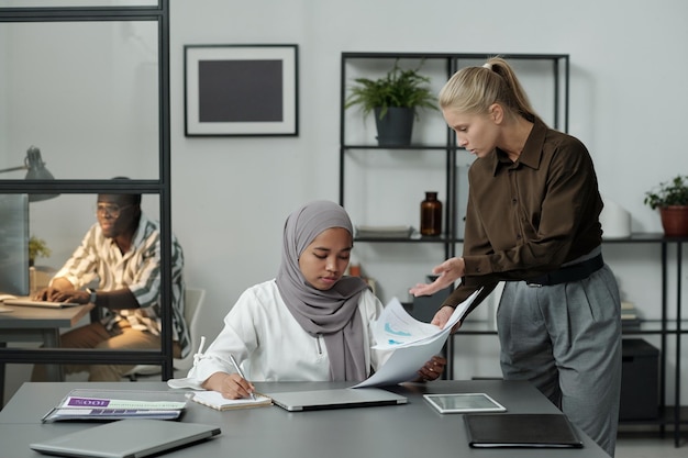 Jeune patronne réprimandant son subordonné en hijab tout en montrant ses documents