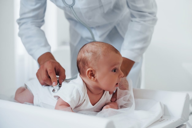 Le jeune pédiatre est avec le petit bébé dans la clinique pendant la journée.