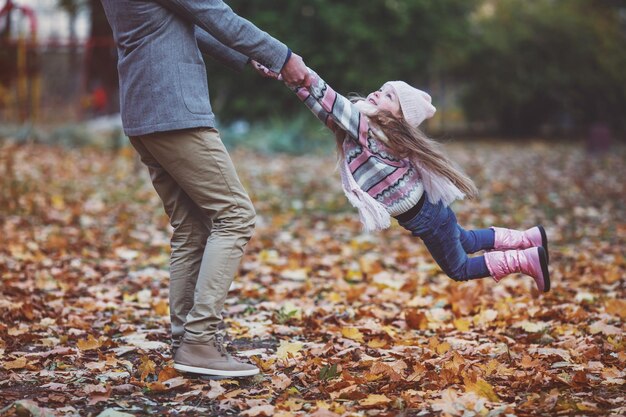Jeune père de famille heureux et sa fille lors d'une promenade dans le parc d'automne