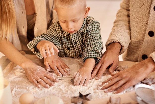 Jeune père de famille, maman et leur petit fils s'amusent à jouer et à cuisiner dans la cuisine