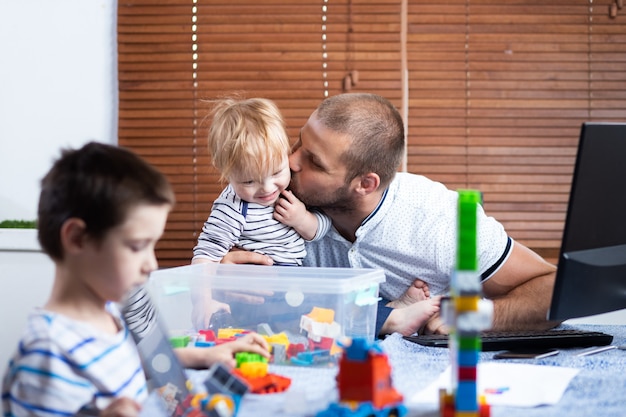 Jeune père homme d'affaires parent interrompt par ses fils enfants alors qu'il travaillait à la maison. Travailler en ligne et élever des enfants en même temps.