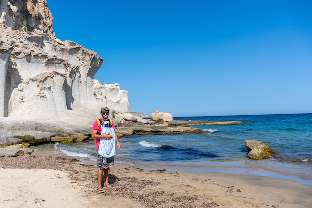 Un jeune père marchant avec son fils le long de la plage d'Enmedio à Cabo de Gata par une belle journée d'été, Almería