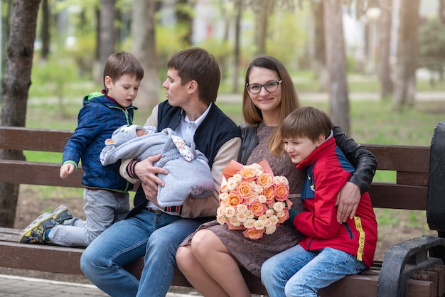 Un jeune père avec un nouveau-né dans ses bras montre à son fils aîné son nouveau frère D