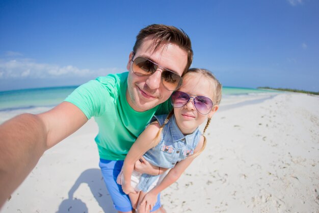 Jeune père et petit enfant prenant une photo de selfie sur la plage