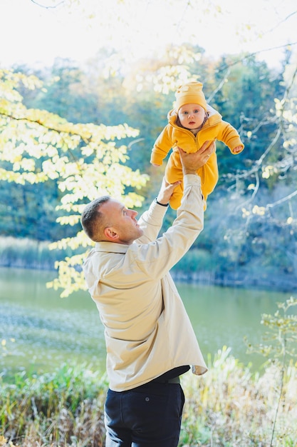 Jeune père et petit fils dans le parc à l'extérieur Père tient et embrasse son fils Père et fils heureux