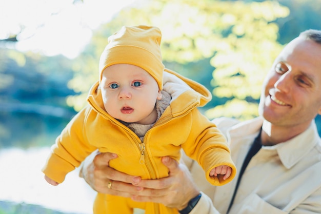 Jeune père et petit fils dans le parc à l'extérieur Père tient et embrasse son fils Père et fils heureux