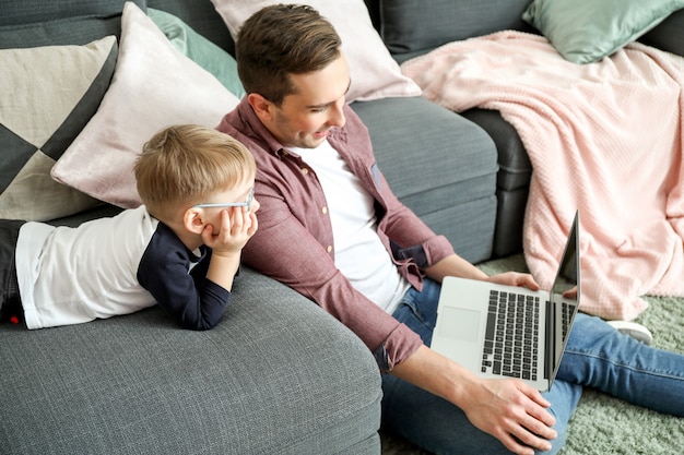 Jeune père avec petit fils regardant des dessins animés à la maison