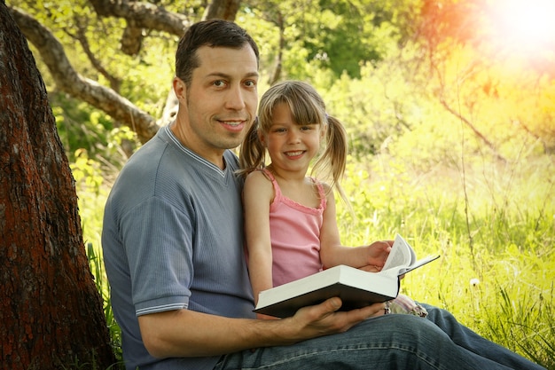 Jeune père avec une petite fille lisant la Bible