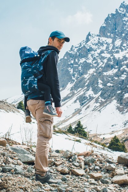 Jeune père de portage attrayant avec son enfant dans un porte-bébé ergonomique voyage dans les montagnes