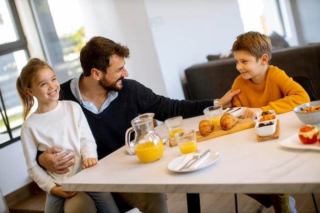 Jeune père prenant son petit déjeuner avec son fils et sa fille à la maison