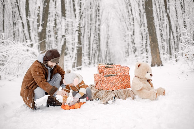 Jeune père avec sa petite fille debout dans la forêt d'hiver