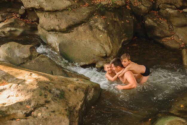 Un jeune père et ses fils se baignent dans une rivière de montagne