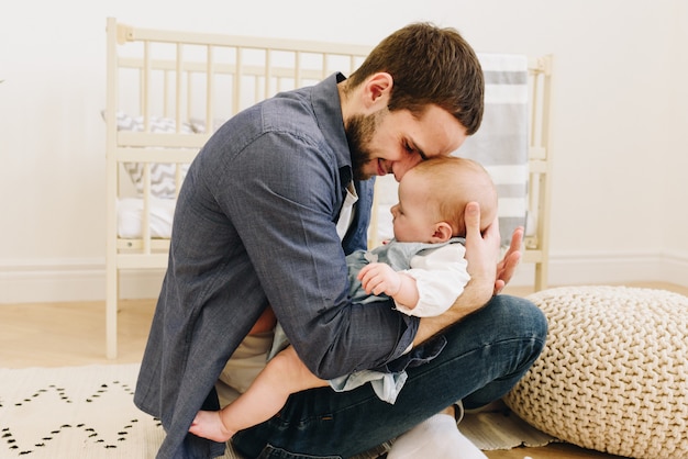 Jeune père avec son bébé en crèche, la tenant doucement