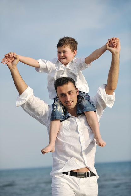 un jeune père et son fils heureux s'amusent et profitent du temps sur la plage au coucher du soleil et représentent une famille saine et un concept de soutien