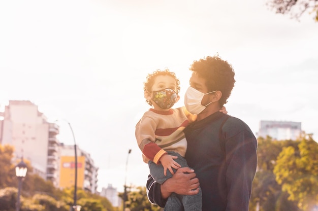 Jeune père avec son fils sur ses bras dans un parc jouant et interagissant avec le concept de la fête des pères