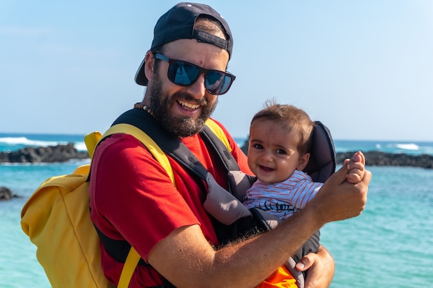 Un jeune père avec son fils en vacances sur la passerelle en bois au bord de la mer sur l'Isla de Lobos, au large de la côte nord de l'île de Fuerteventura, aux Canaries. Espagne