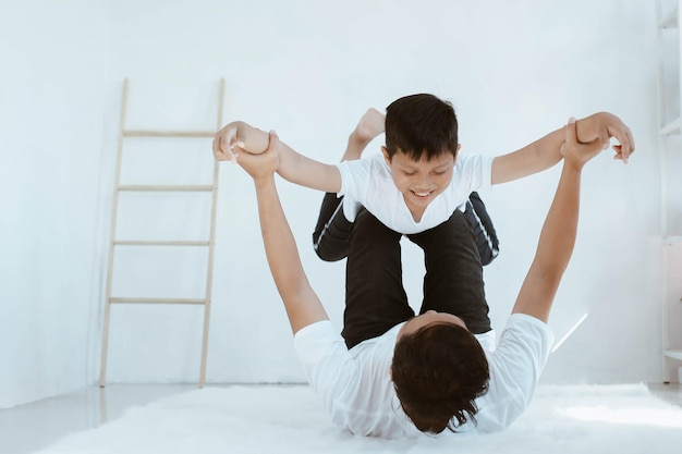 Jeune père soulevant son fils en t-shirt blanc tout en posant un avion volant passer du temps ensemble à h