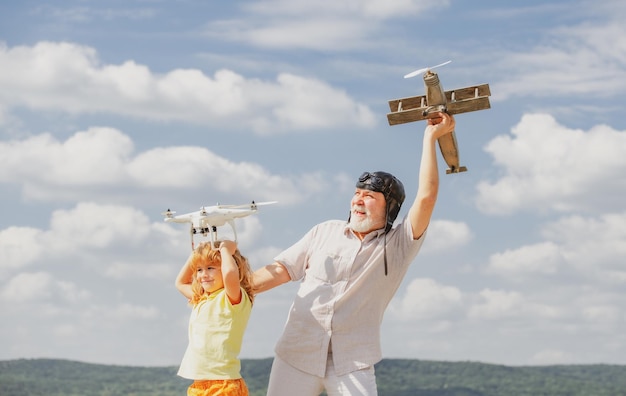 Jeune petit-fils et vieux grand-père avec avion et drone quadcopter sur ciel bleu et nuages backgrou