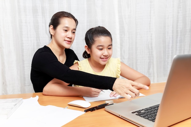 Jeune petite fille asiatique à l'aide d'un crayon pour faire ses devoirs avec sa mère