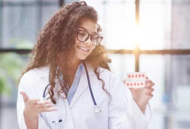 Jeune pharmacienne tenant des pilules alors qu'elle était assise à la table du bureau