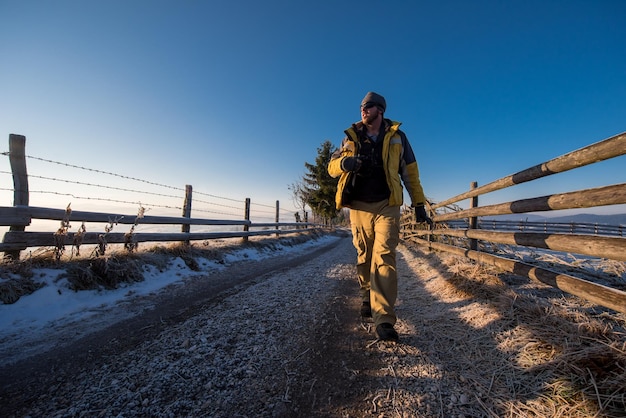 jeune photographe appréciant la belle nature tout en marchant sur une route de campagne pendant une journée d'hiver ensoleillée