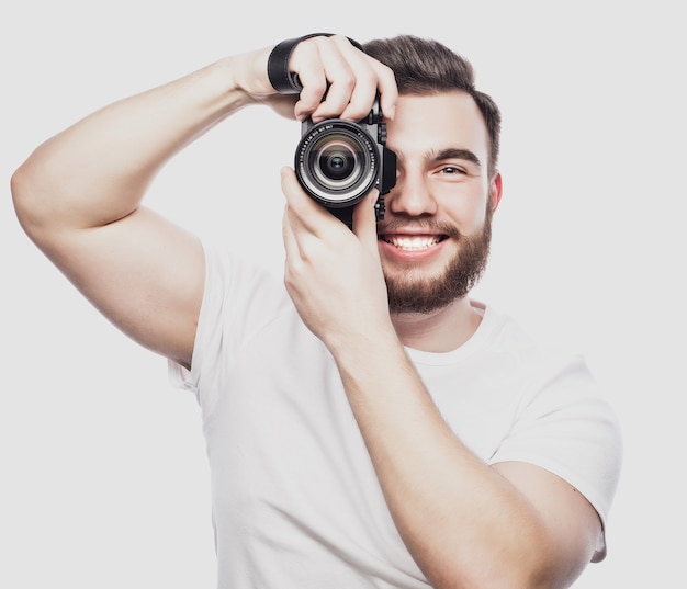 jeune photographe barbu prenant des photos avec un appareil photo numérique.