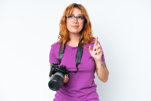 Photo jeune photographe caucasien femme isolée sur fond blanc avec les doigts croisés et souhaitant le meilleur