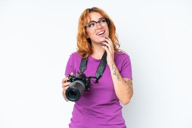 Jeune photographe caucasien femme isolée sur fond blanc levant les yeux en souriant