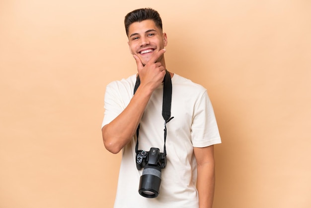 Jeune photographe caucasien homme isolé sur fond beige souriant