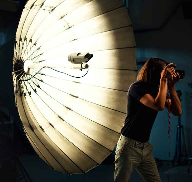 Photo jeune photographe debout devant un parapluie réfléchissant