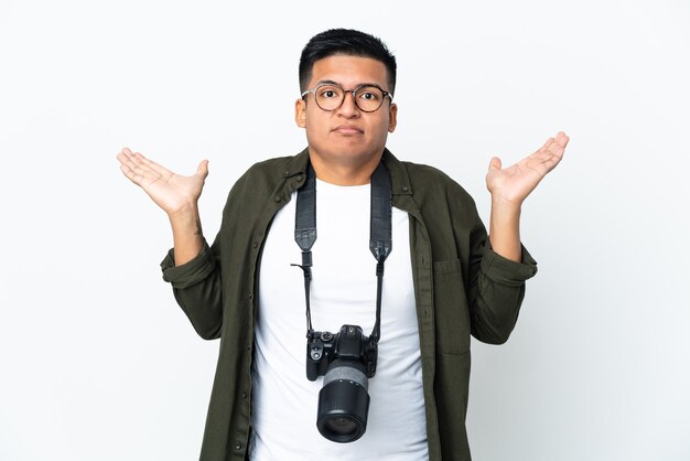 Jeune photographe équatorien isolé sur fond blanc ayant des doutes en levant les mains