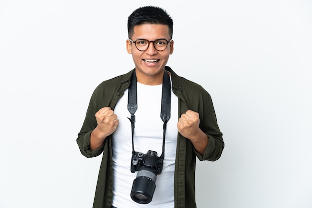 Jeune photographe équatorien isolé sur un mur blanc célébrant une victoire en position de vainqueur