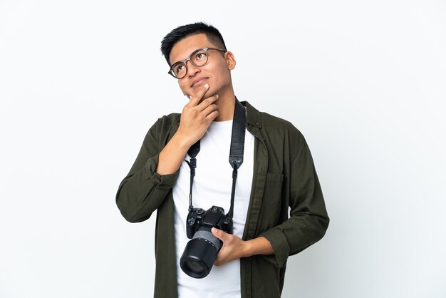 Jeune photographe équatorien isolé sur un mur blanc en regardant en souriant