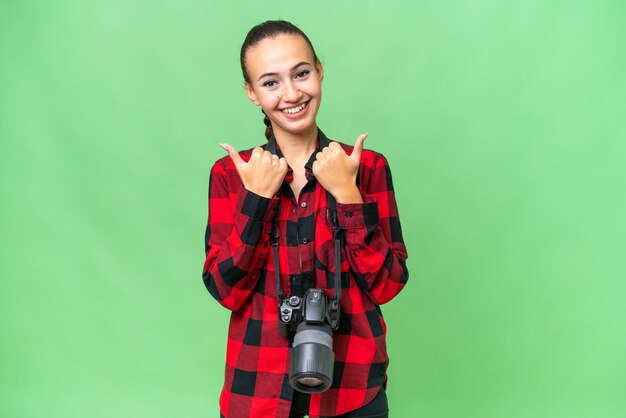 Jeune photographe femme arabe sur fond isolé avec le geste du pouce levé et souriant