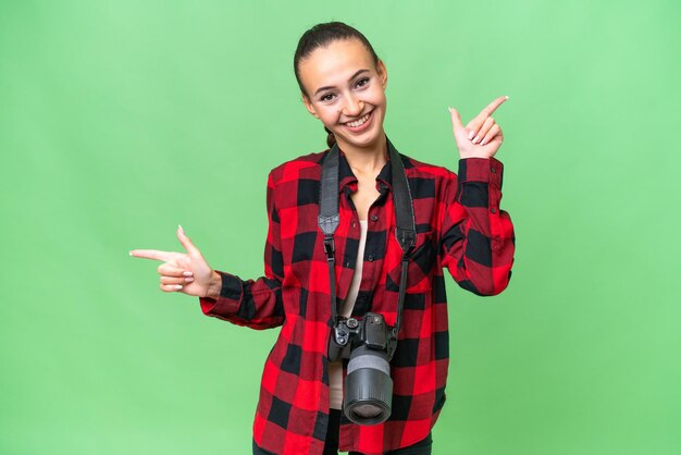 Jeune photographe femme arabe sur fond isolé pointant du doigt les latéraux et heureux